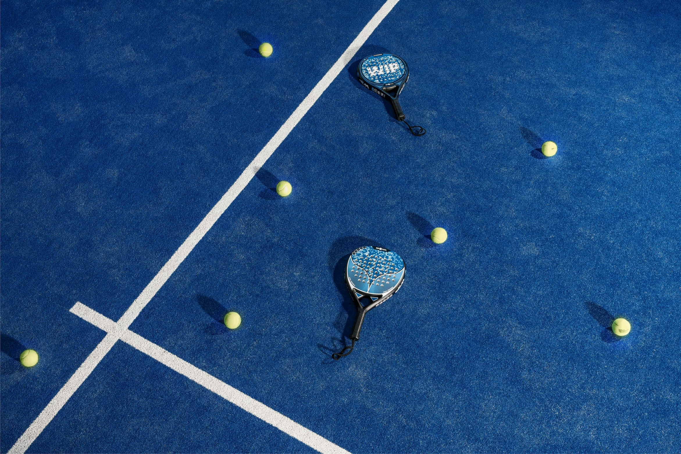 Padelschläger und Bälle auf einem blauen Court