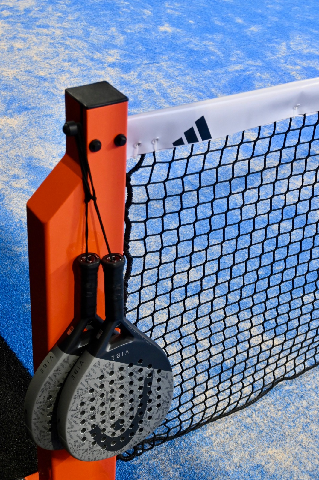 Padelschläger am Netz eines Indoor-Doublecourts